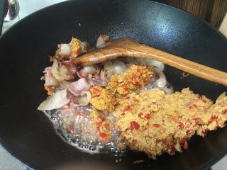 渣海椒腊肉,腊肉铲在边上，倒入渣海椒在油里迅速翻炒，这里动作要快，渣海椒很容易成一坨、糊了锅底。让渣海椒炒进油后，再混合腊肉一起翻炒均匀。