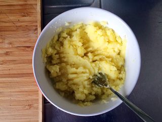 土豆牛肉丸子烩饭,用勺子或叉子将蒸熟的土豆捣碎成泥。